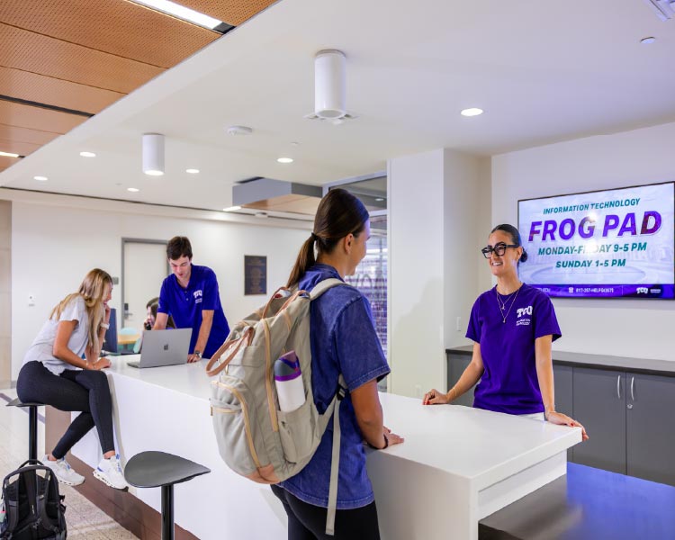 Student worker helping customer with computer at front desk