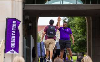 Orientation leader and student high-fiving on steps at the BLUU
